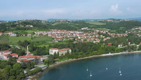 Aerial-truck-shot-rising-up-as-it-flys-along-the-coast-of-the-city-of-Ankaran,-Slovenia