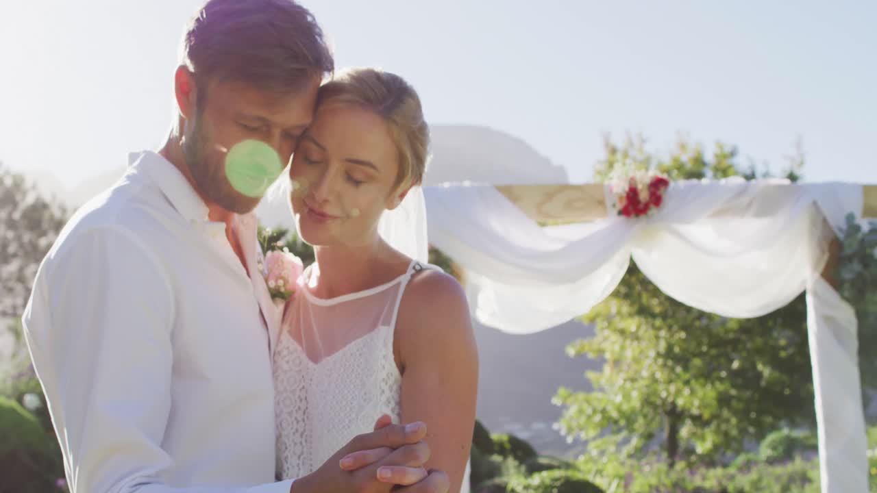 retrato de una feliz pareja de recién casados caucásicos, bailando frente al altar al aire libre