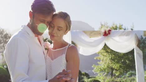 portrait of happy caucasian newly wed couple, dancing in front of altar outdoors