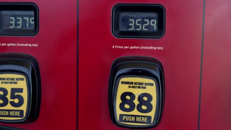 red and black gas pumps with prices super high over three dollars, panning left to right to show unleaded, medium, and premium grade fuel prices - in 4k slow motion