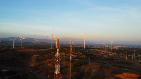 windmill-turbine-farm-and-electric-pylon-5g-tower-station-for-clean-energy-supply,-Vietnam-remote-countryside-aerial-view