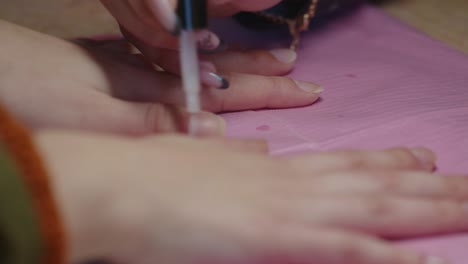 close up, anonymous manicurist applying transparent nail polish on client's nails, slow motion