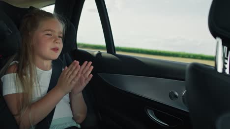 Female-caucasian-child-singing-and-clapping-hands-while-driving-in-the-car-.