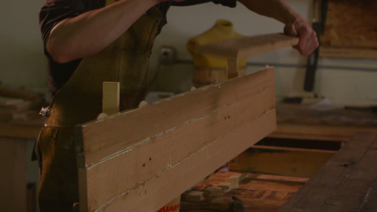 un carpintero pega tablas en un taller