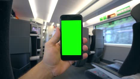 mano sosteniendo un teléfono con una pantalla verde en el tren