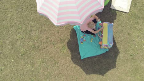 Slowly-descending-above-a-mother-and-child-enjoying-a-warm-afternoon-in-the-shade-of-an-umbrella,-aerial