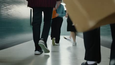 students walking down a school hallway with books on the floor