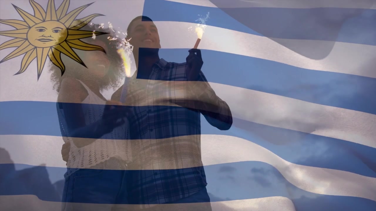 Paar feiert mit Wunderkerzen und schwenkt uruguayische Flagge