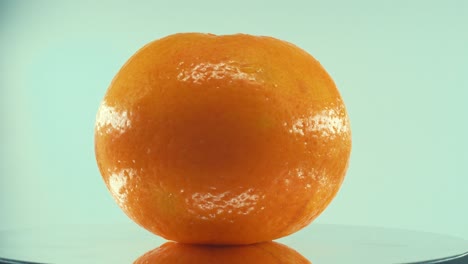 a close up shot of a clementine orange fruit on a reflecting rotating 360 stand, studio lighting, slow motion, 4k video