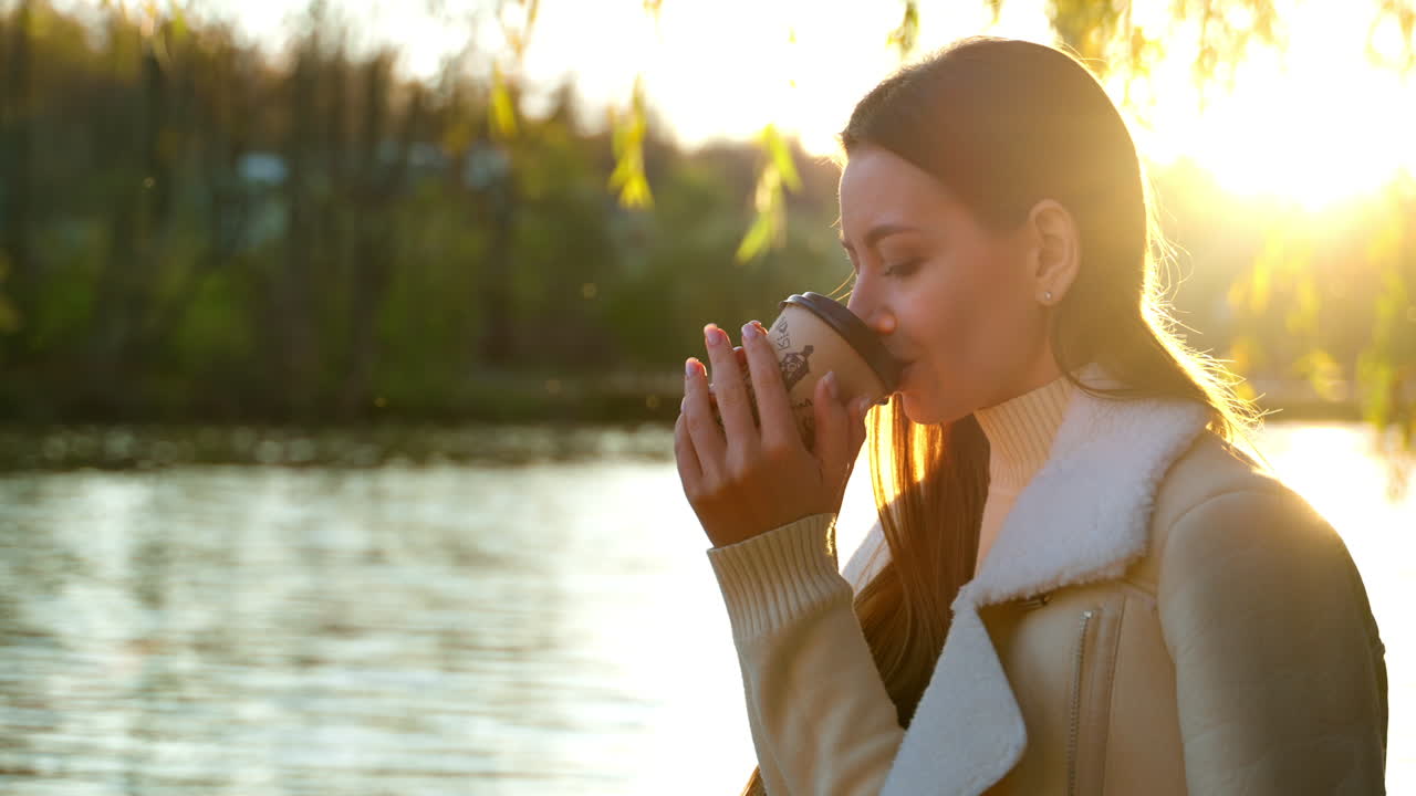 Woman enjoying coffee at sunset by the lake