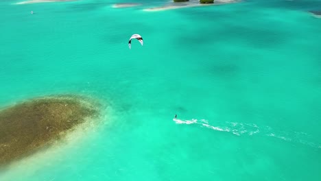 Imágenes-Aéreas-Siguen-A-Amigos-Kitesurf-En-Agua-De-Mar-Turquesa,-Parque-Natural-Prístino-Los-Roques