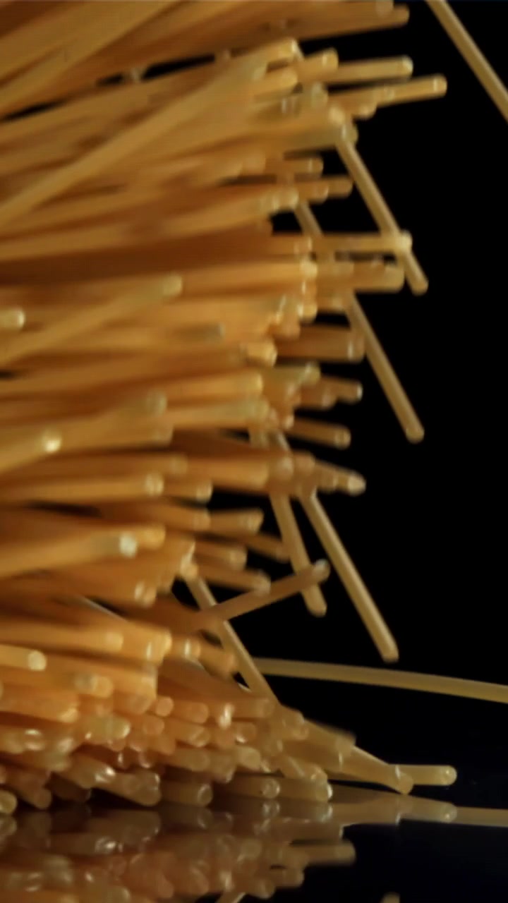 Fili di Spaghetti Secchi che Cadono al Rallentatore su Sfondo Nero