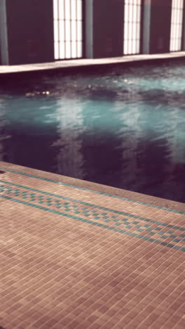 a vintage indoor swimming pool with tile walls and a blue water surface