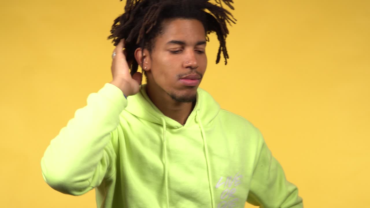 A thoughtful young black male student in a green hoodie deeply thinking