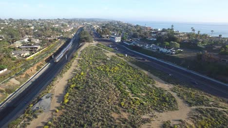 high stationary aerial over an amtrak train traveling beside the pacific ocean near san diego