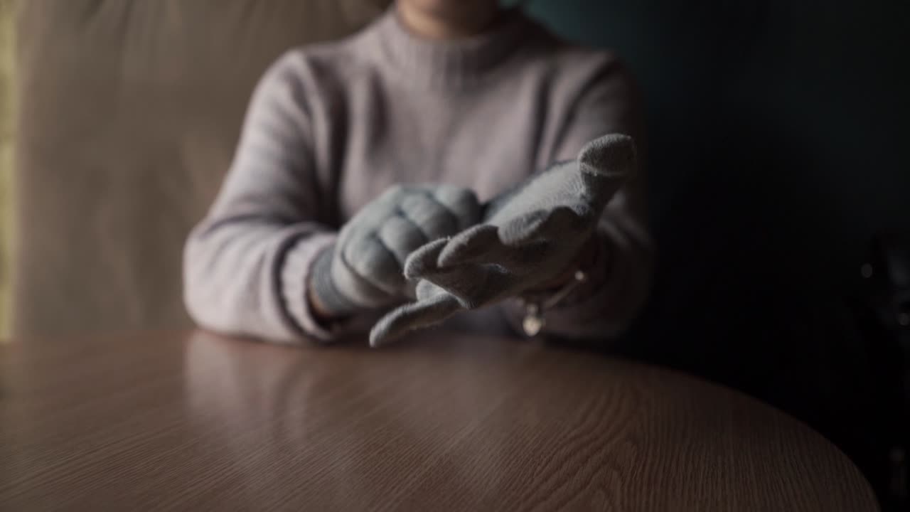 Girl puts winter gloves on her hands.