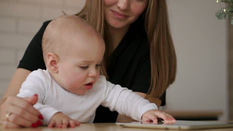 Young-Caucasian-Mother-using-Tablet-with-her-Baby-son.-Slow-Motion-120-fps.-Mother-showing-her-Child-digital-Tablet.-Children-and-Technology-concept.-Toddler-boy.-Cinematic-family