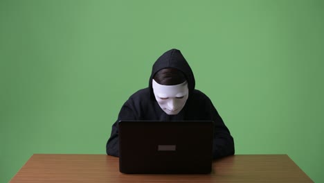 young teenage boy computer hacker against green background