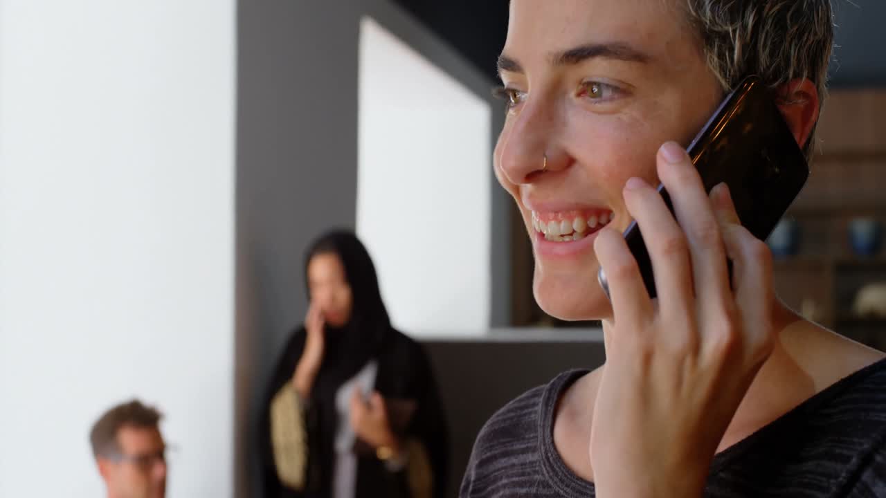 ejecutivo hablando por teléfono móvil mientras un colega discute en una tableta digital en el fondo 4k