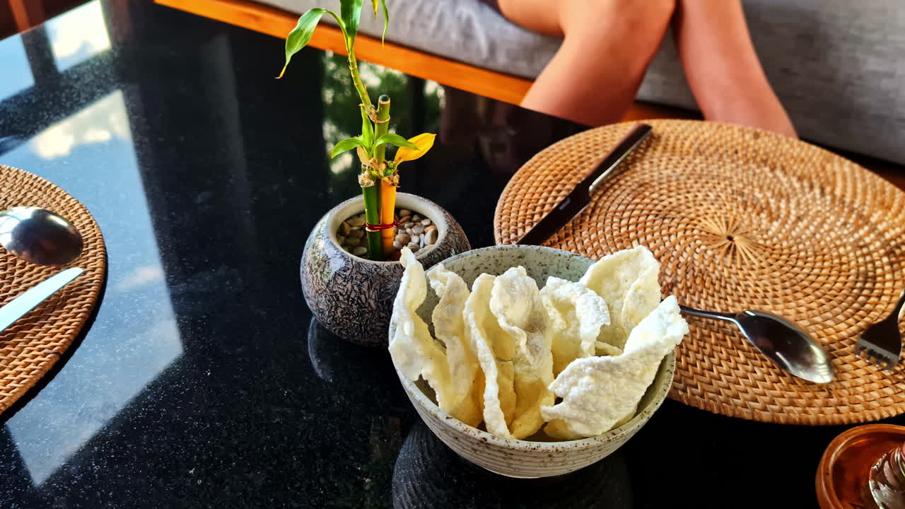 A quiet dining moment in Kuta Selatan as a hand picks up a cracker from the table