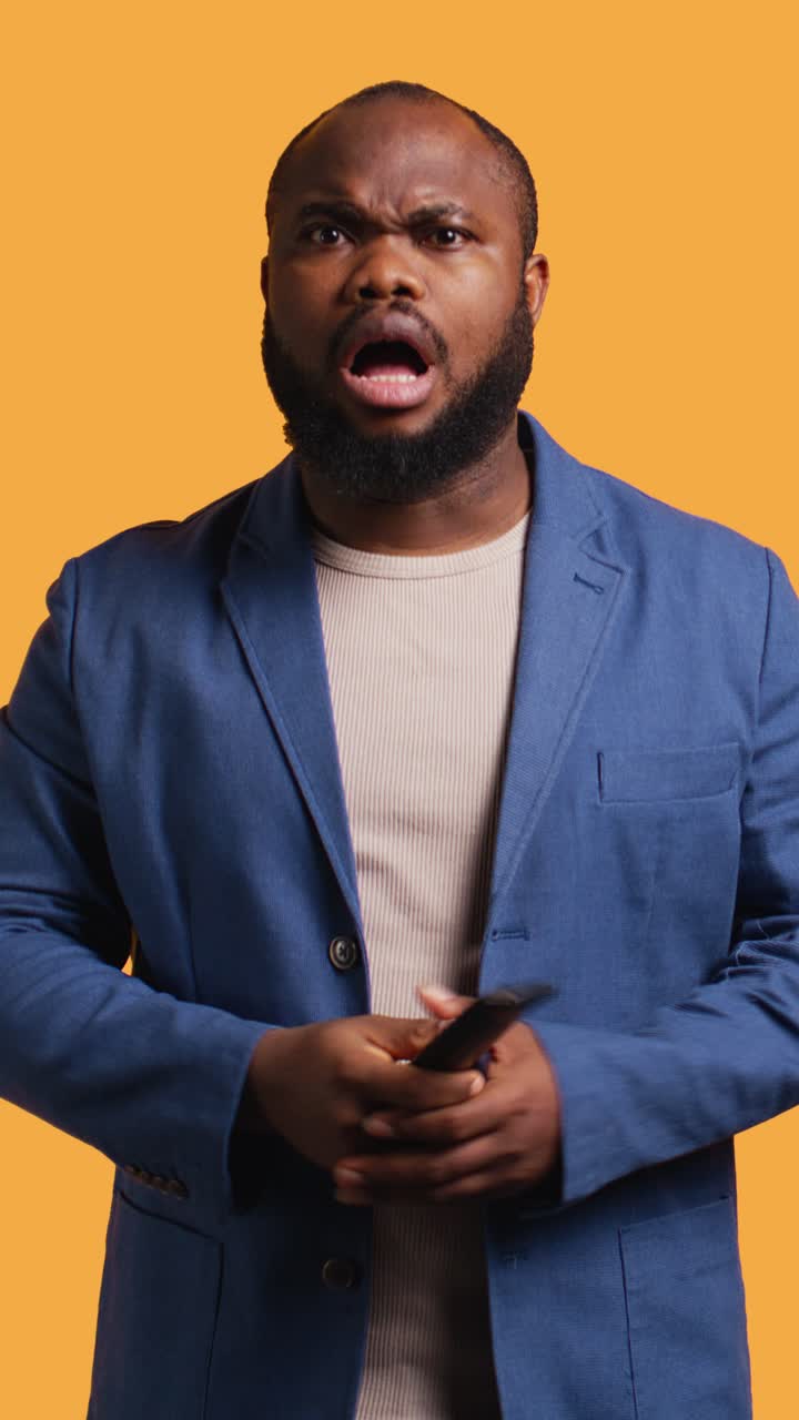 African American Man Reacting with Surprise and Anger While Holding Remote Control