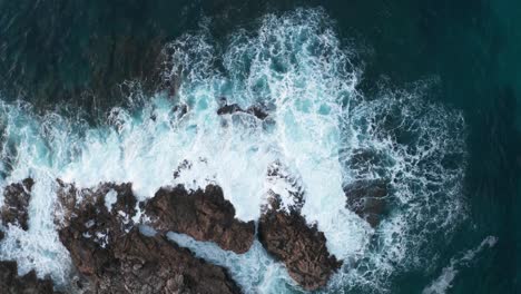 Drone-Top-Down-Shot-waves-crashing-onto-rocky-shore-in-Mallorca-Island