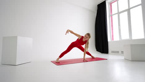 joven atractiva practicando yoga aislada en fondo blanco en ropa deportiva roja . concepto de vida saludable y equilibrio natural entre el cuerpo y el desarrollo mental. longitud completa