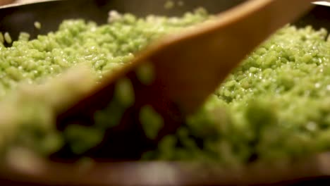 close up view of a wooden spoon stirring green spinach risotto, still, slomo