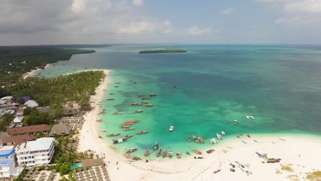 Vista-Aérea-De-Barcos-Africanos-De-Madera-Parados-En-Aguas-Poco-Profundas-Y-Arenosas-Cerca-De-La-Playa-Costera,-Zanzíbar,-Tanzania,-Toma-De-Lapso-De-Tiempo-A-30-Fps