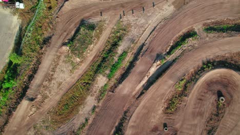 Luftdrohnenaufnahme-Von-Oben-Nach-Unten-über-Einer-Motocross-Strecke,-Die-Das-Streckendesign-Bewundert