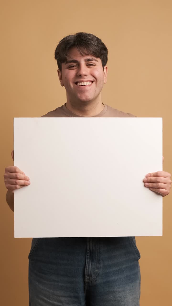 Cheerful man showing blank banner in studio
