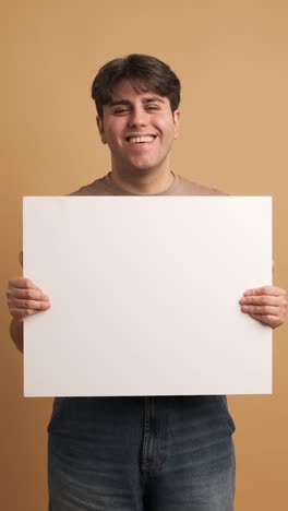 cheerful man showing blank banner in studio