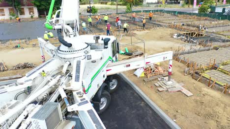 Rising-Aerial-Over-Construction-Site-With-Giant-Crane-And-Workers-Pouring-Concrete-Foundation-In-Ventura-California