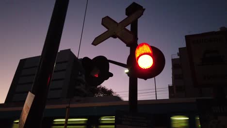 luces rojas parpadeando, tren nocturno al atardecer pasando por el horizonte de fondo en el centro de la ciudad