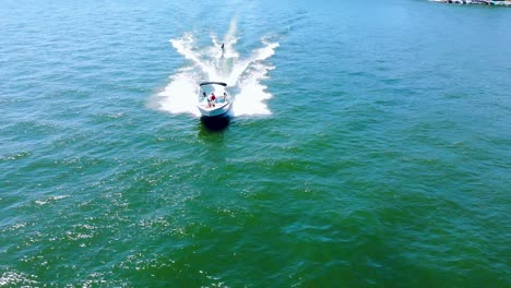 backward moving aerial showing tourist tied behind high speed motor boat and enjoying water skiing