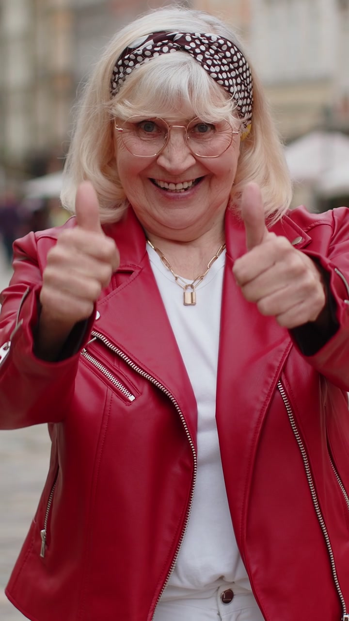 Donna anziana che mostra il pollice in alto come segno positivo qualcosa di buono feedback positivo in strada della città