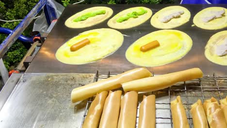 close-up of a vendor crafting mini pancakes with various fillings on a hot grill.