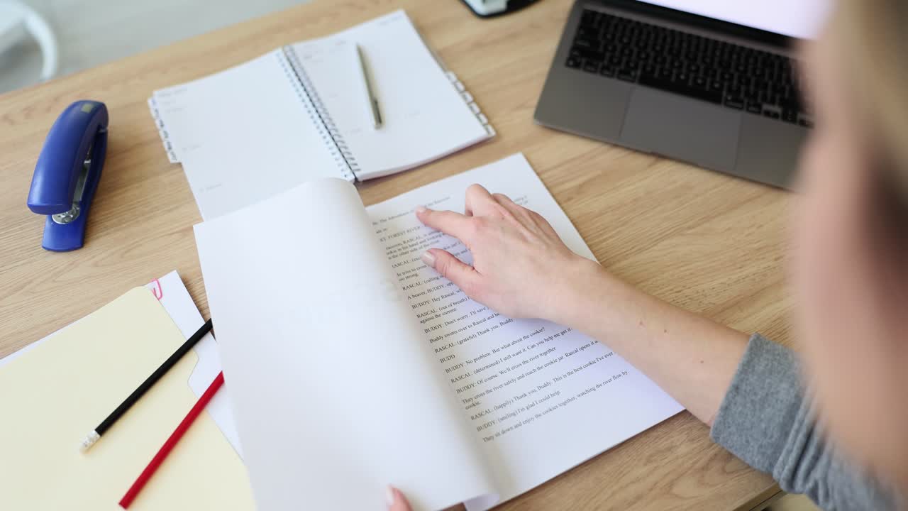 Female language editor opens script lying on wooden table