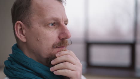 bearded man in scarf looks at wintry landscape. concentrated man observes tranquil beauty of nature while thinking about future. gentleman reflection