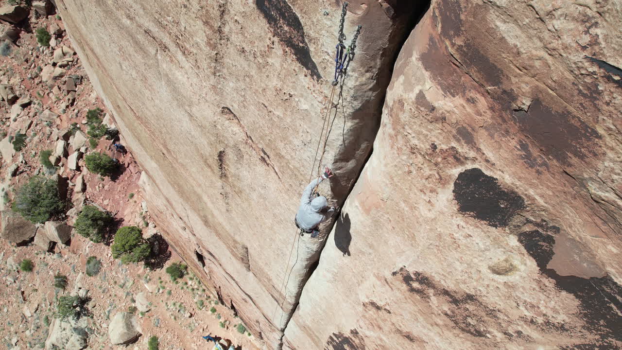 Vista aerea di uno scalatore, corde e crepa in ripida roccia verticale, sport di arrampicata, ripresa drone dall'alto