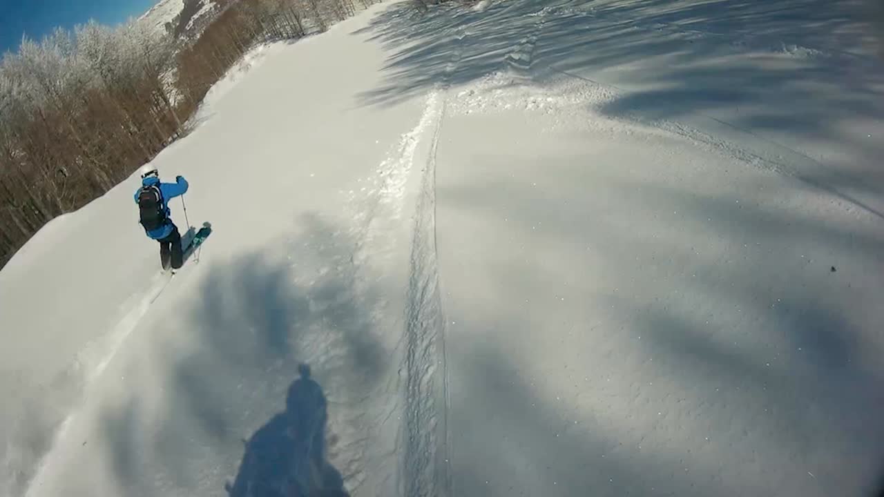 Two guys skiing and snowboarding down a slope.