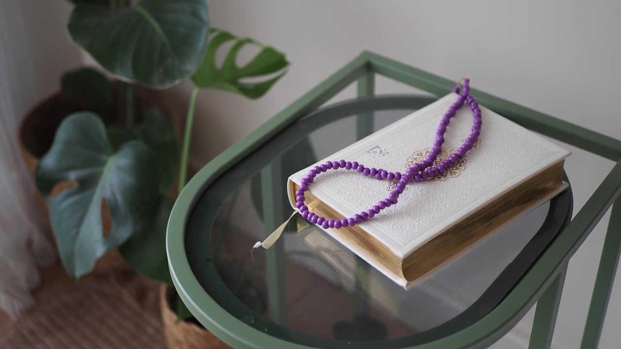 Sacro Corano e rosario viola su un tavolino moderno