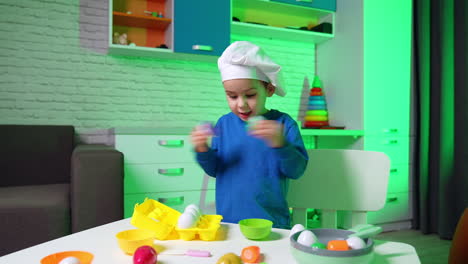 charming toddler boy plays with food toys. little cute baby chef cooking.