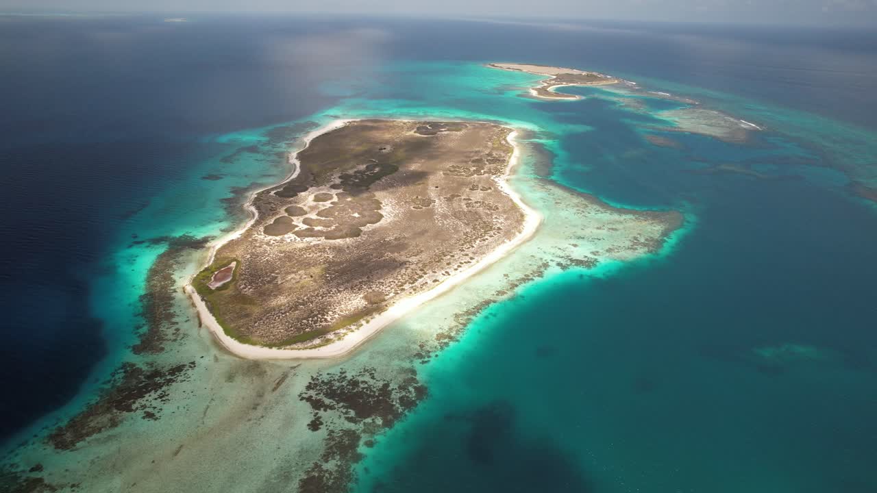 Noronky island surrounded by turquoise water and coral reefs, clear day, aerial view