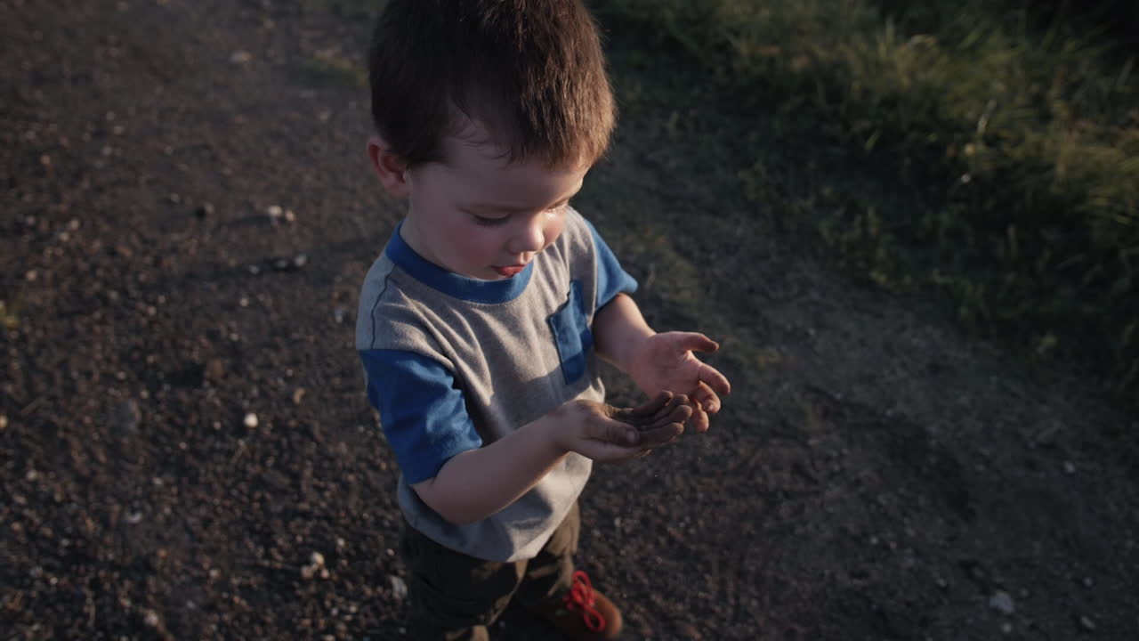 젊은, 행복한 소년이 밖에서 놀고 있으며, 영화 속 느린 동작으로 해가 지는 동안 을 던지고 있습니다.