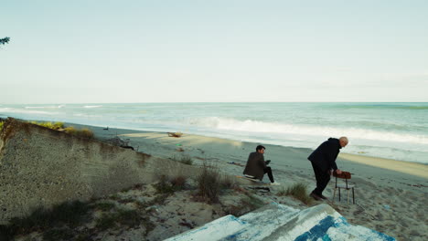 father sits on the beach watching the slow life of the waves crashing