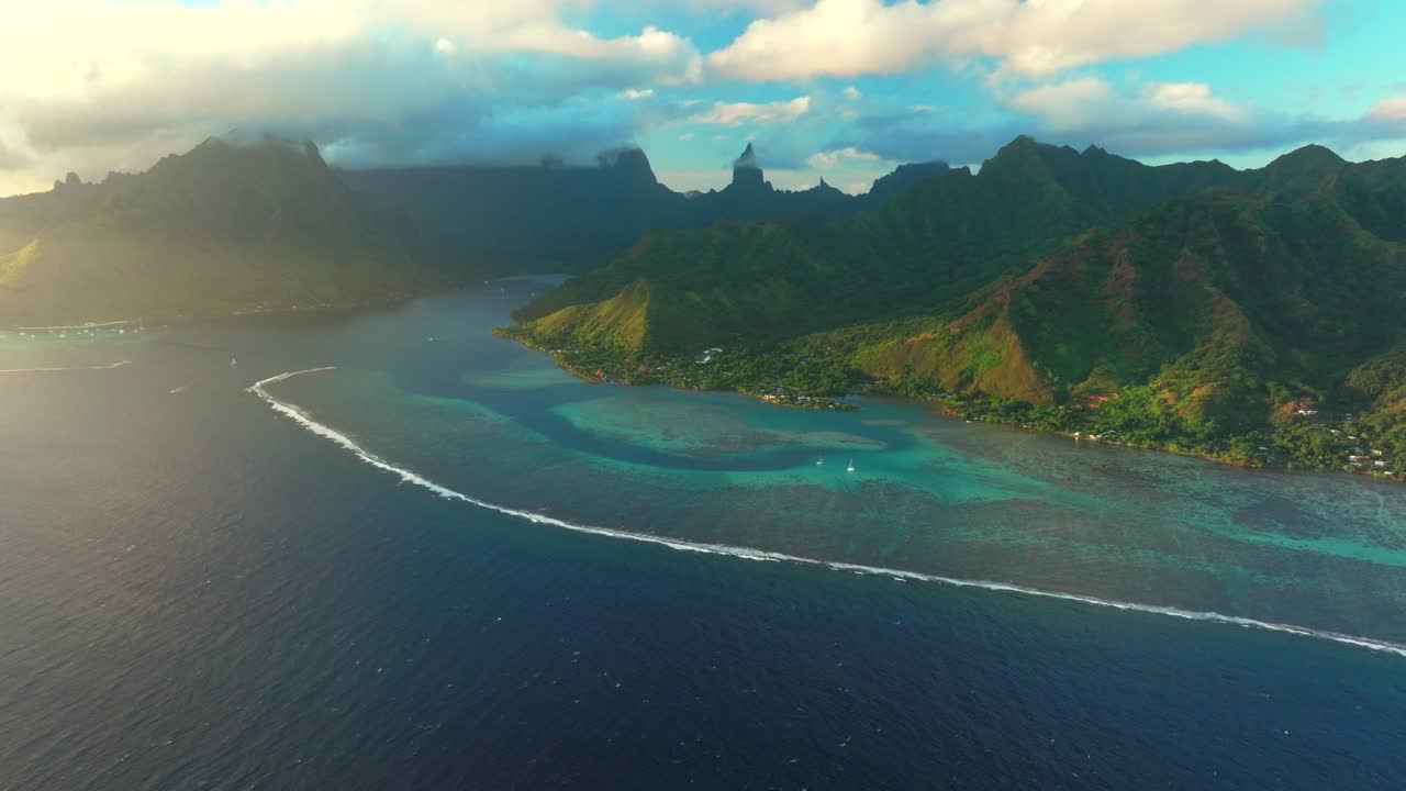 Sunset Cooks Opunohu bay Moorea French Polynesia aerial drone bright blue lagoon coral reef Mount Mauaroa Tohivea Rotui jagged mountain peaks Haapiti Paopao South Pacific Ocean sailboats forward pan