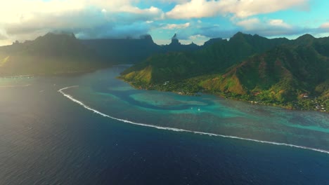 sunset cooks opunohu bay moorea french polynesia aerial drone bright blue lagoon coral reef mount mauaroa tohivea rotui jagged mountain peaks haapiti paopao south pacific ocean sailboats forward pan