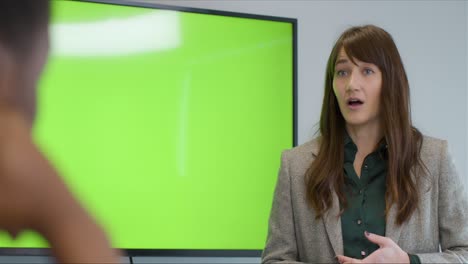 mujer de negocios hablando con colegas con una televisión de pantalla verde
