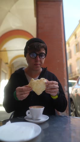 person eating bread and drinking coffee outdoors